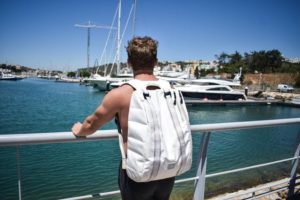 man wearing a backpack near yacht