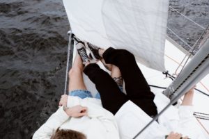a couple laying on a yacht's bow, under the hammock
