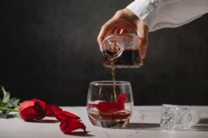 Person pouring whiskey in glass