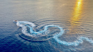 boat leaving a trail as the sun sets